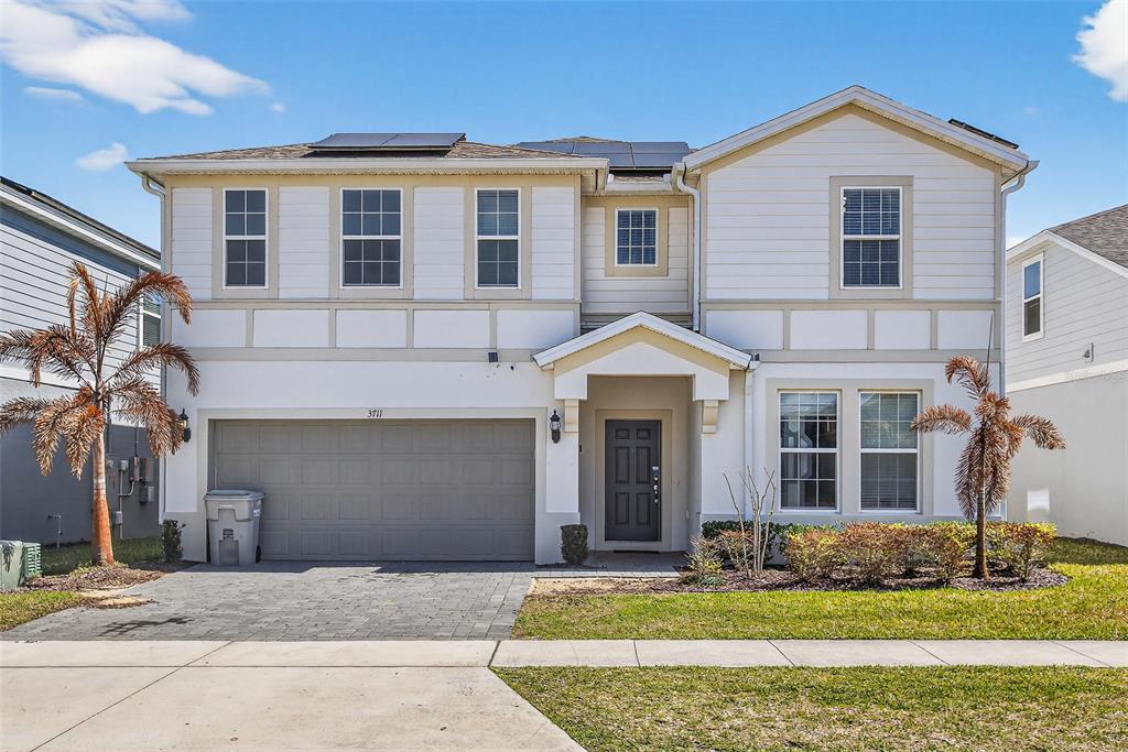 A two-story suburban house with a gray garage, white siding, and a paved driveway — 3711 LANA AVENUE, DAVENPORT, FL