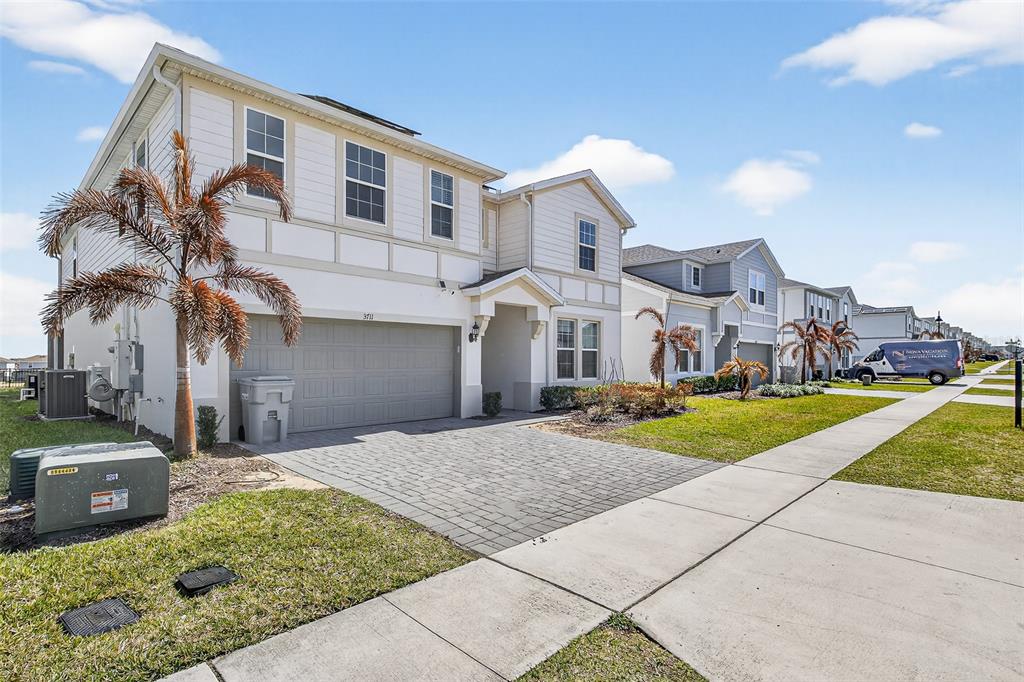 A two-story house with a paved driveway, a two-car garage, and a small palm tree — 3711 LANA AVENUE, DAVENPORT, FL