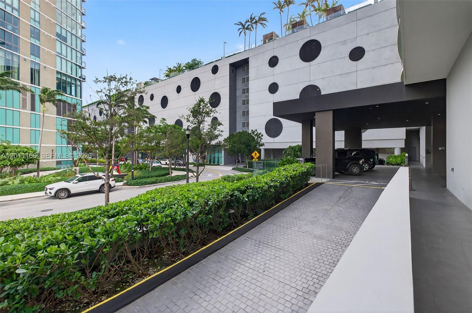 A modern building exterior features a white facade with large circular cutouts and landscaping — 3131 NE 7th Ave # 4503, Miami FL 33137, MIAMI, FL