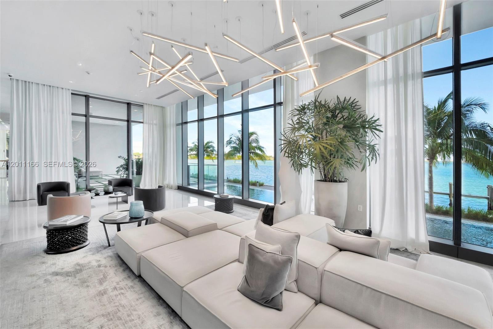 A modern living room features a large sectional sofa, unique geometric lighting, and floor-to-ceiling windows — 3131 NE 7th Ave # 4503, Miami FL 33137, MIAMI, FL