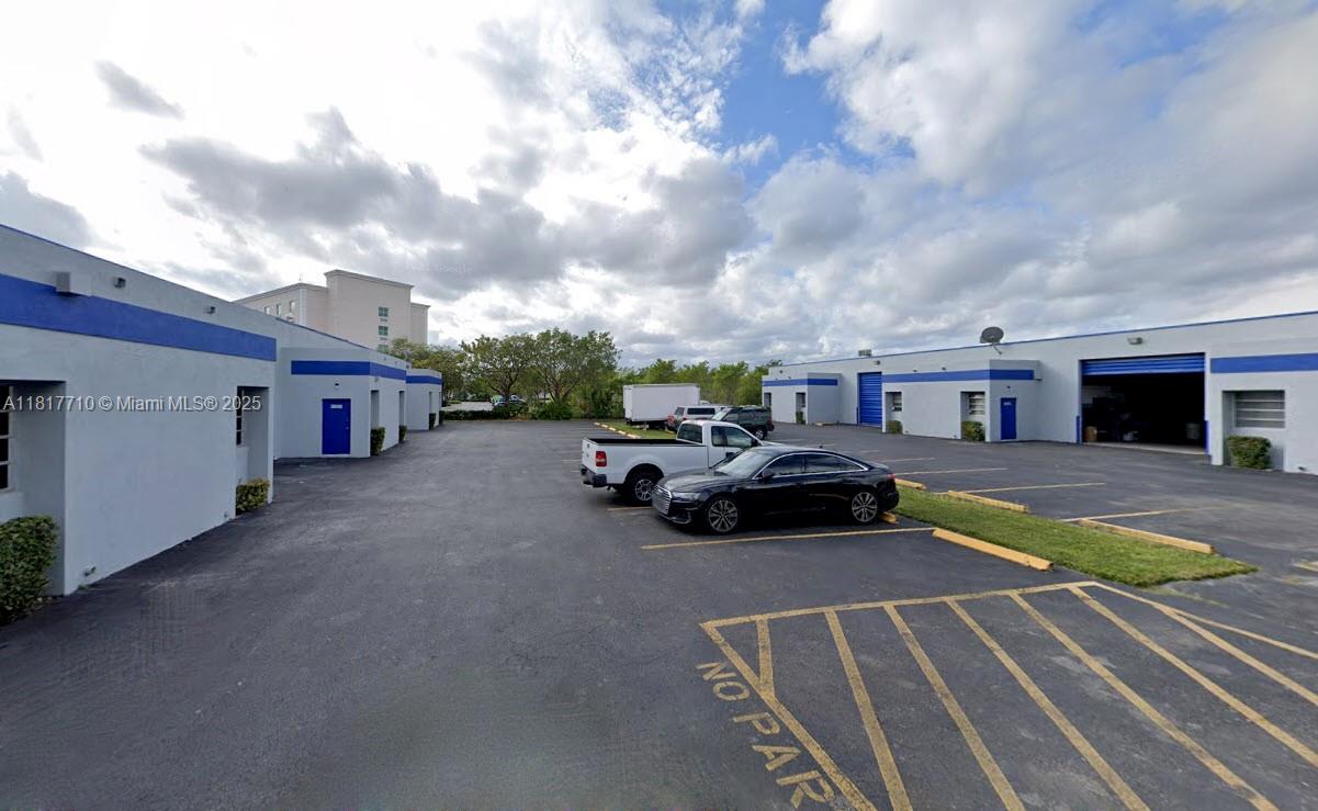 An exterior view of a commercial warehouse complex with a paved parking lot — 13552 SW 129th St, Miami FL 33186, MIAMI, FL