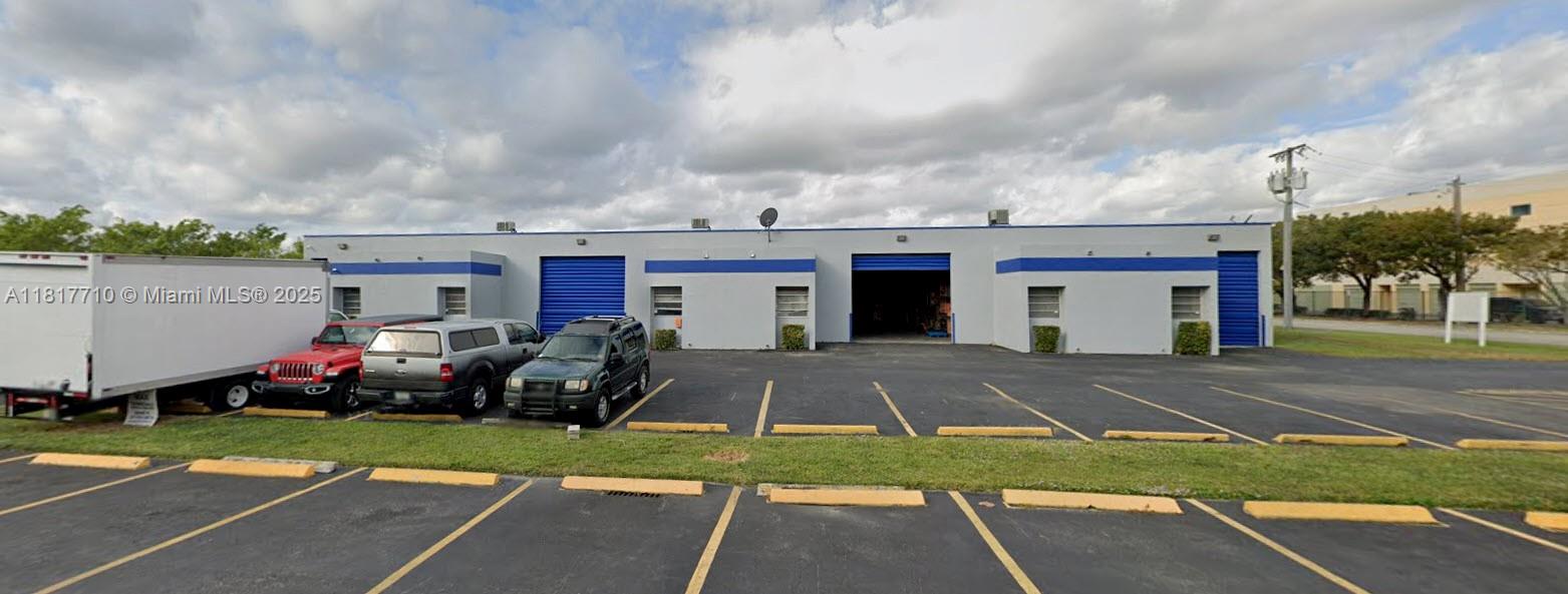A single-story commercial warehouse building with blue roll-up doors and a paved parking lot — 13552 SW 129th St, Miami FL 33186, MIAMI, FL