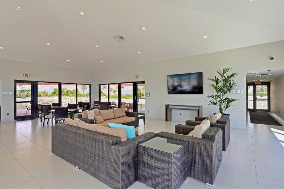 A spacious lounge area features wicker sofas, a wall-mounted television, and floor-to-ceiling glass doors — 5550 N Ocean Drive # 8a, Singer Island FL 33404, SINGER ISLAND, FL