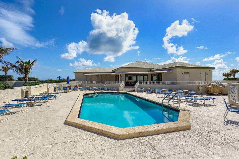 An outdoor swimming pool with lounge chairs on a patio in front of a building — 5550 N Ocean Drive # 8a, Singer Island FL 33404, SINGER ISLAND, FL