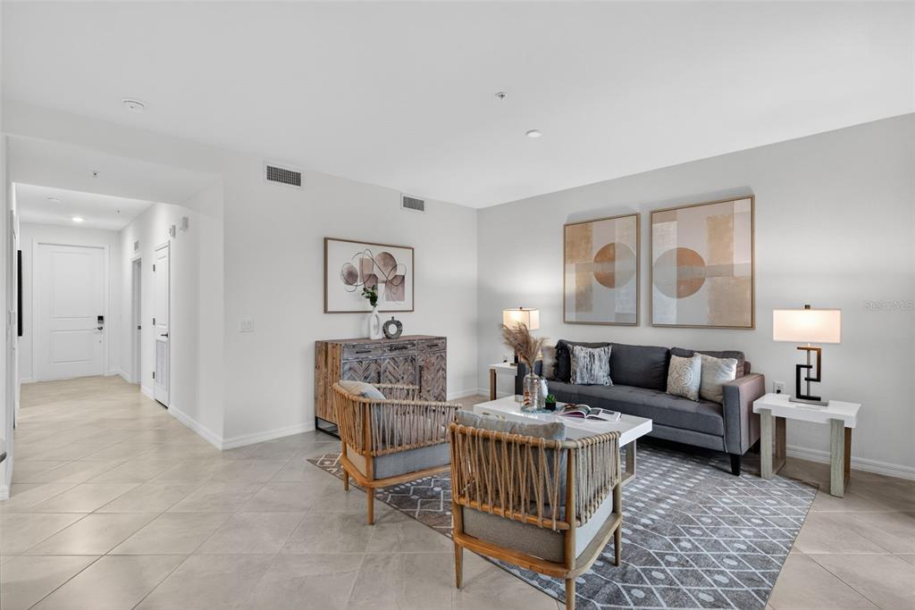 A living room features a grey sofa, two rattan chairs, and a patterned area rug — 14201 HERITAGE LANDING BOULEVARD UNIT 1312, PUNTA GORDA, FL