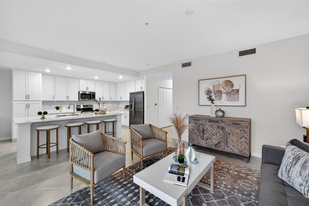 An open-concept kitchen with white cabinetry and an island overlooks a living area with seating — 14201 HERITAGE LANDING BOULEVARD UNIT 1312, PUNTA GORDA, FL