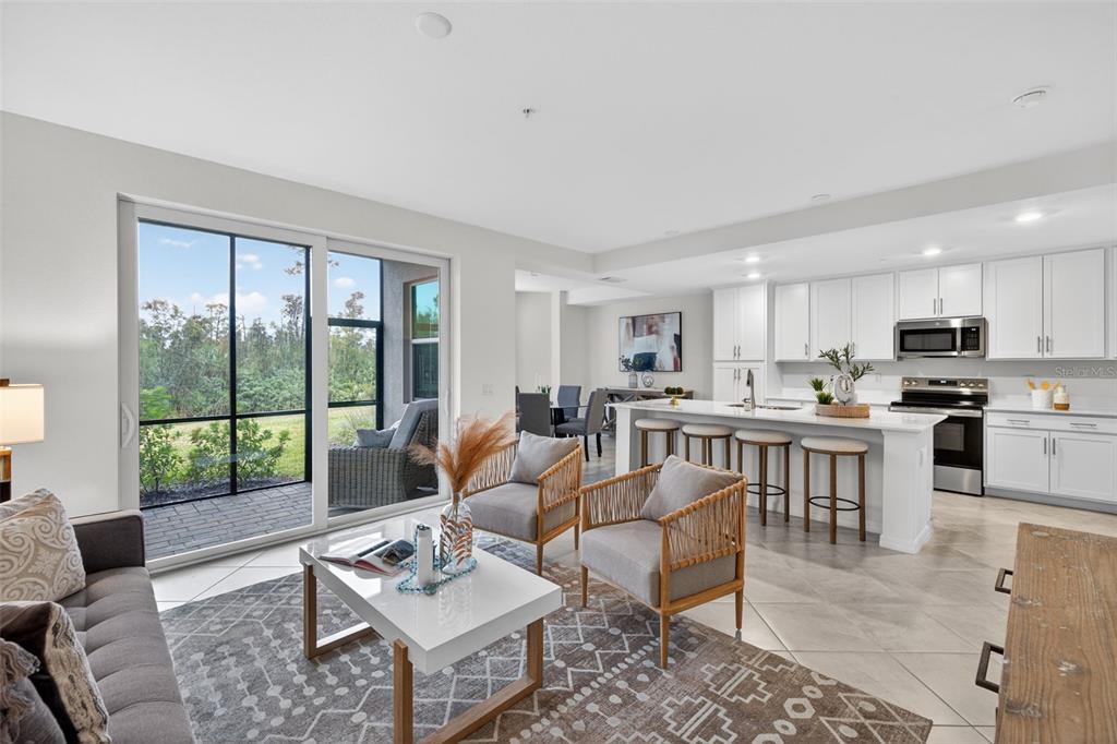 An open-concept living room and kitchen with white cabinetry, a center island, and sliding doors — 14201 HERITAGE LANDING BOULEVARD UNIT 1312, PUNTA GORDA, FL