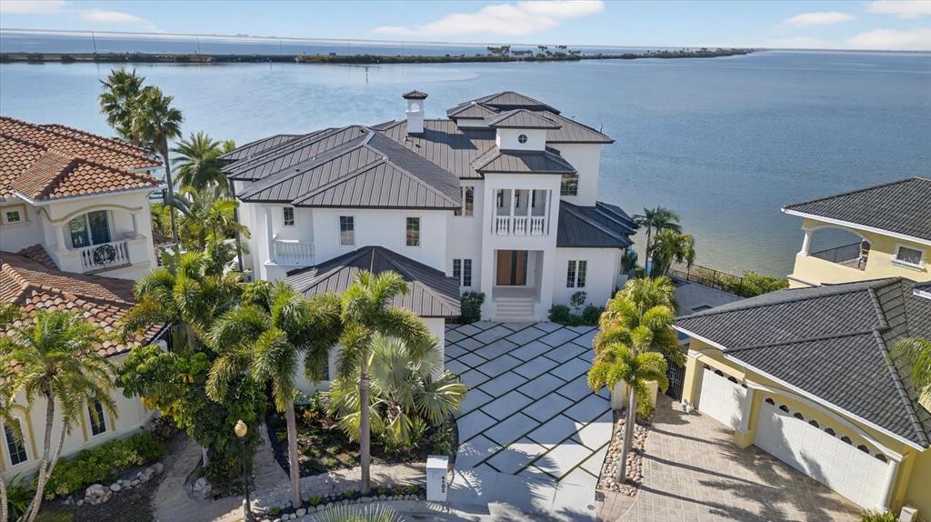 An aerial view of a white multi-story waterfront house with a geometric paved driveway — 4102 CAUSEWAY VISTA DRIVE, TAMPA, FL
