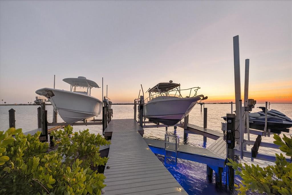 A wooden dock extends into the water with two boats and a jet ski on lifts — 4102 CAUSEWAY VISTA DRIVE, TAMPA, FL