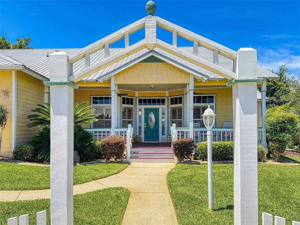 A yellow house with a white pergola entrance and a teal front door — 2815 BAY SIDE DRIVE, NEW SMYRNA BEACH, FL