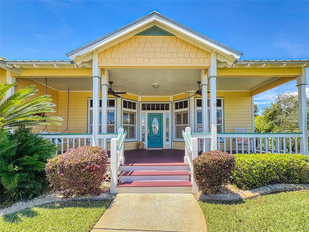 A yellow house with a covered front porch, teal door, and steps leading to the entrance — 2815 BAY SIDE DRIVE, NEW SMYRNA BEACH, FL