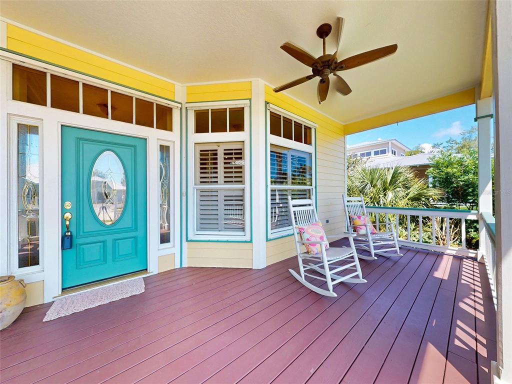 A covered porch features a teal front door, two white rocking chairs, and wooden decking — 2815 BAY SIDE DRIVE, NEW SMYRNA BEACH, FL