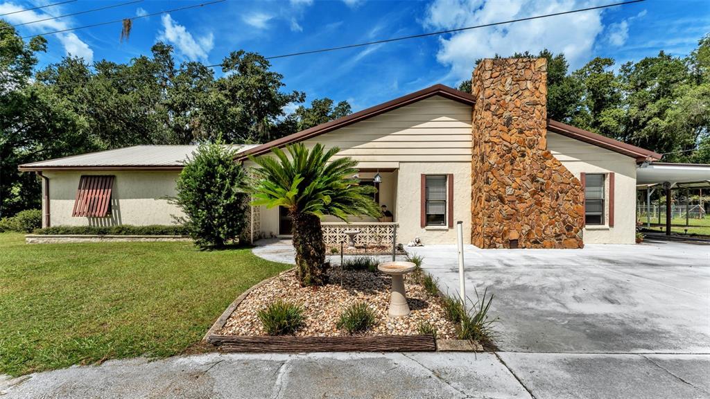 A single-story house features a stone chimney, light-colored siding, and a landscaped front yard — 1301 LANIER ROAD, LAKELAND, FL