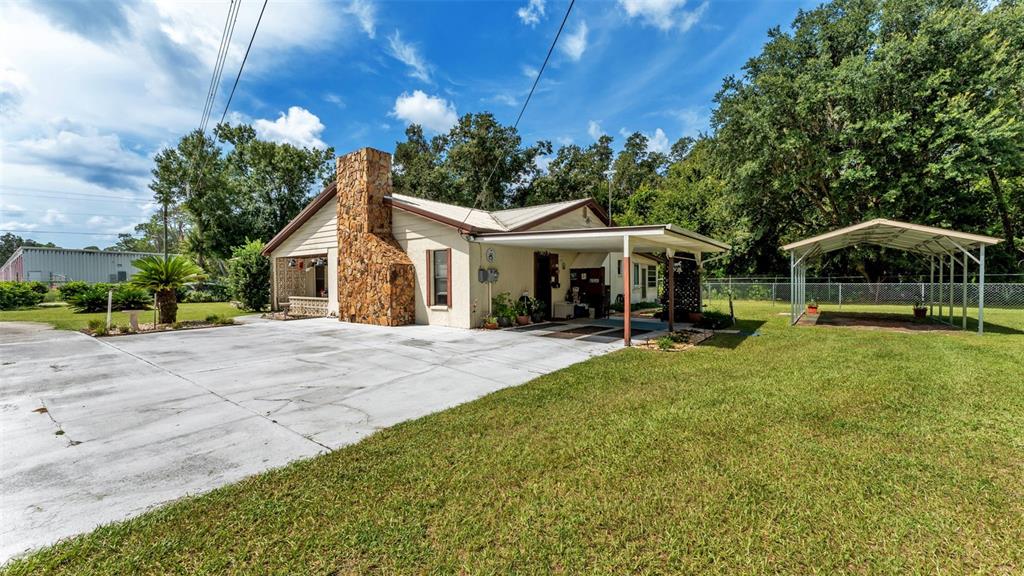 A single-story house with a stone chimney, a concrete driveway, and a detached metal carport — 1301 LANIER ROAD, LAKELAND, FL