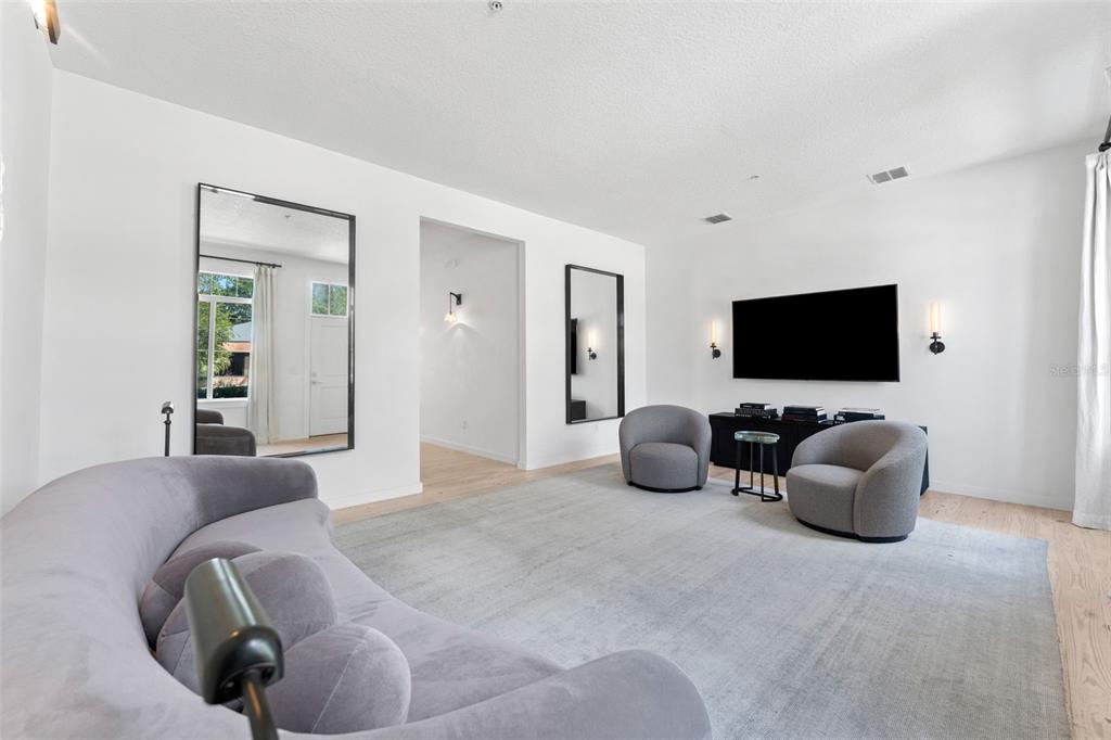 A living room features a curved sofa, two armchairs, a television, and two large mirrors — 771 LAKE BALDWIN LANE, ORLANDO, FL