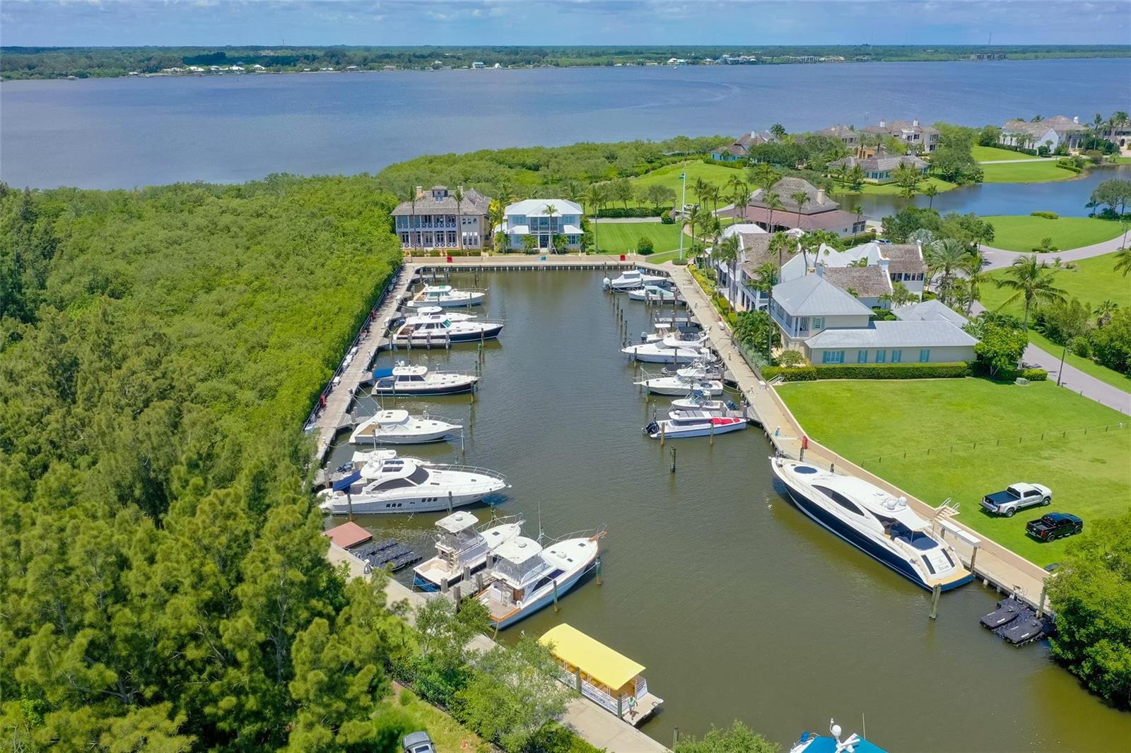An aerial view shows a marina with multiple docked boats surrounded by lush green landscaping — 9260 E Marsh Island Drive, Vero Beach FL 32963, VERO BEACH, FL
