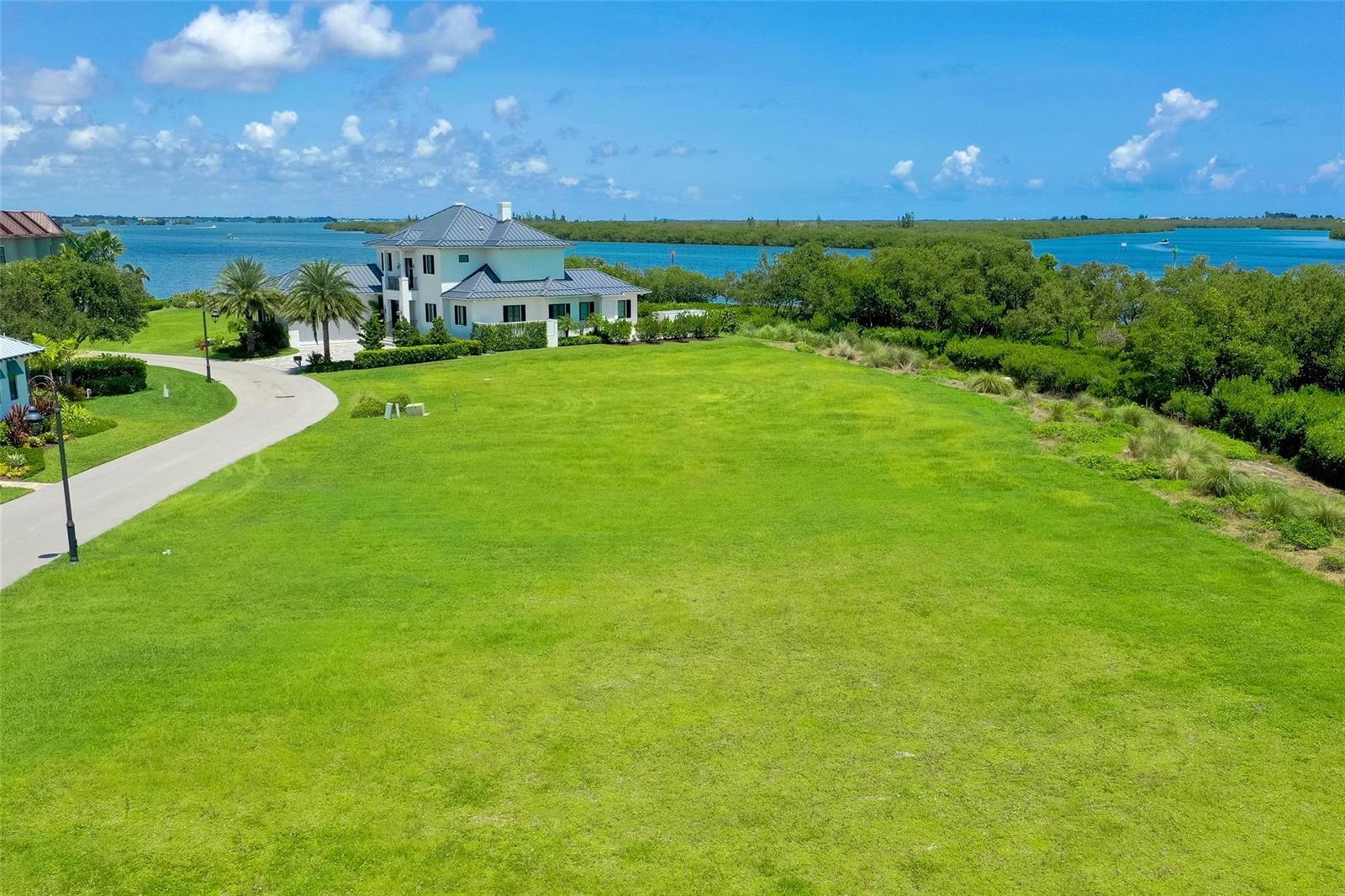 An aerial view shows a large grassy lot next to a white house and water — 9260 E Marsh Island Drive, Vero Beach FL 32963, VERO BEACH, FL