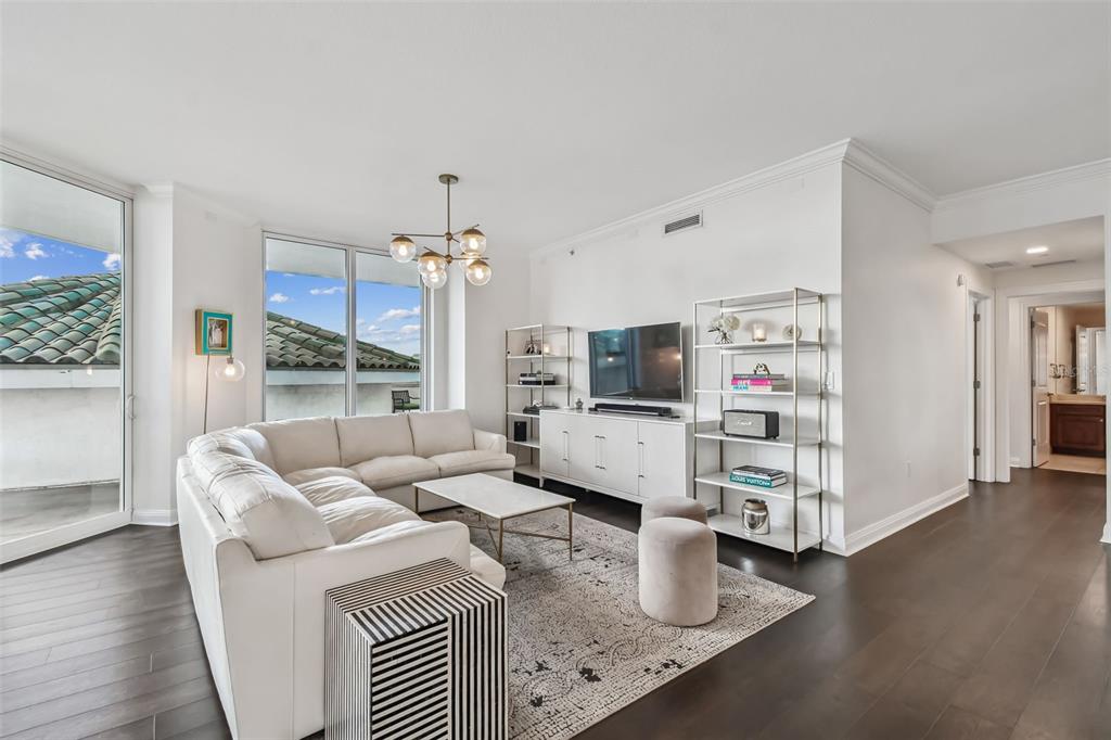 A living room features a white sectional sofa, a television console, and dark wood floors — 450 KNIGHTS RUN AVENUE UNIT 502, TAMPA, FL