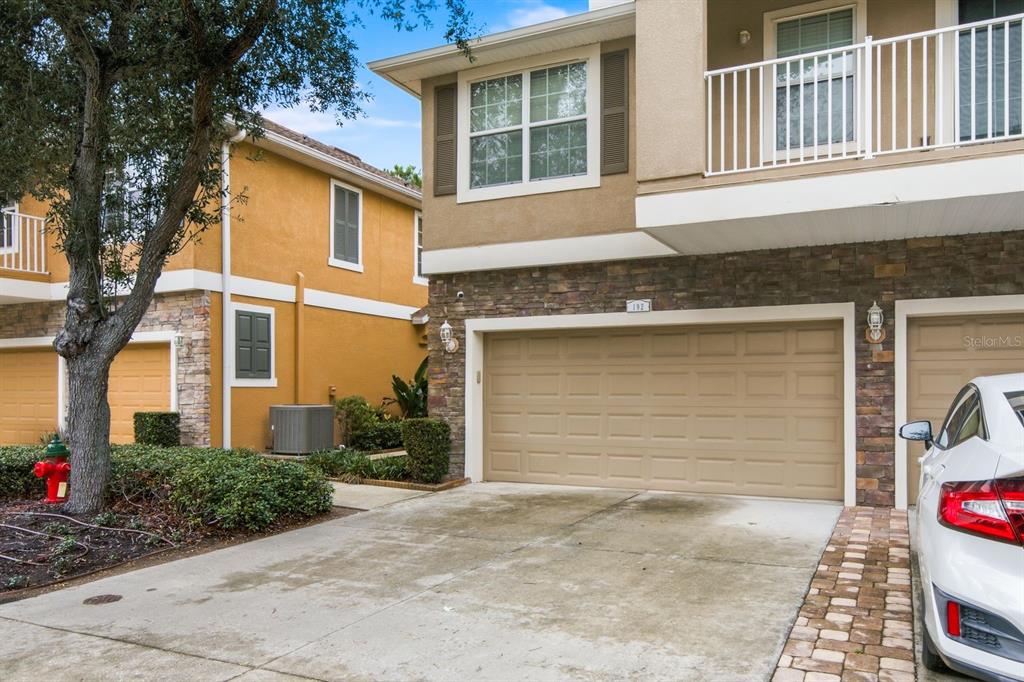 A two-story townhouse exterior features a tan garage, stone accents, and a white balcony railing — 7001 INTERBAY BOULEVARD UNIT 192, TAMPA, FL