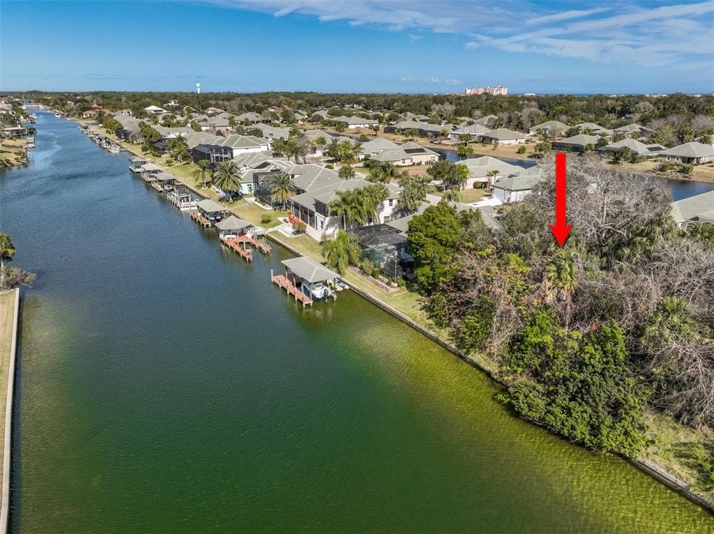 An aerial view shows a wooded waterfront lot next to a residential canal and homes — 49 LONGVIEW WAY N, PALM COAST, FL