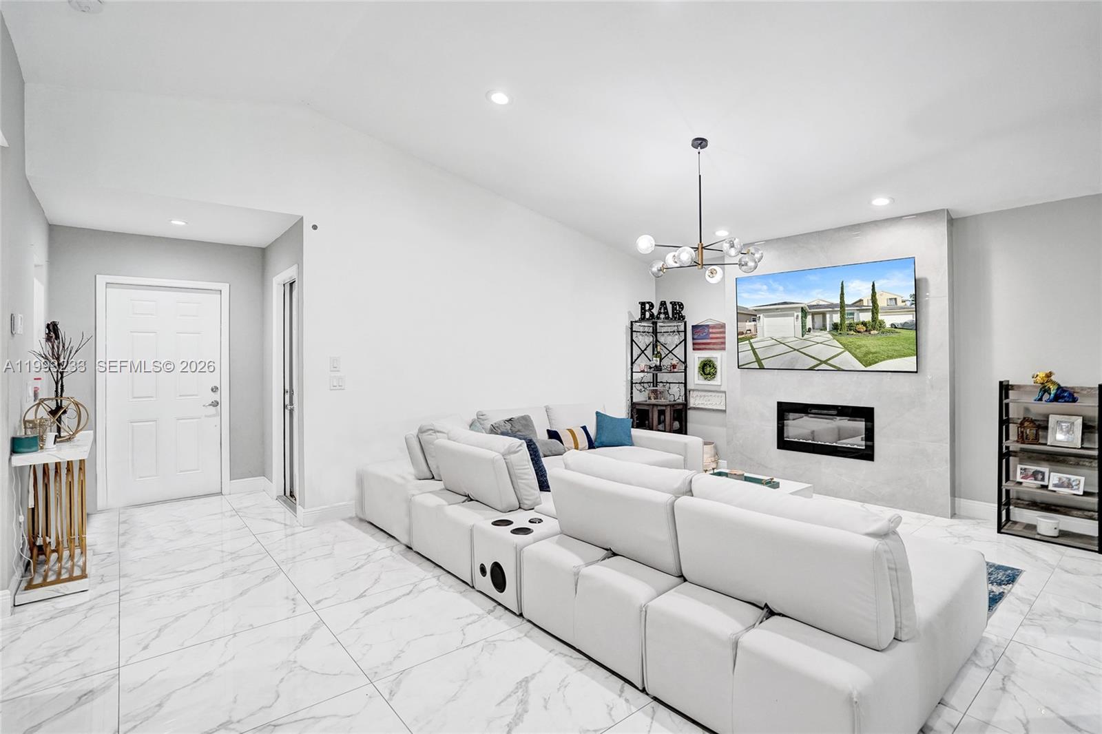 A modern living room features white tile floors, a sectional sofa, and a fireplace wall — 372 W Riverbend Dr, Sunrise FL 33326, SUNRISE, FL