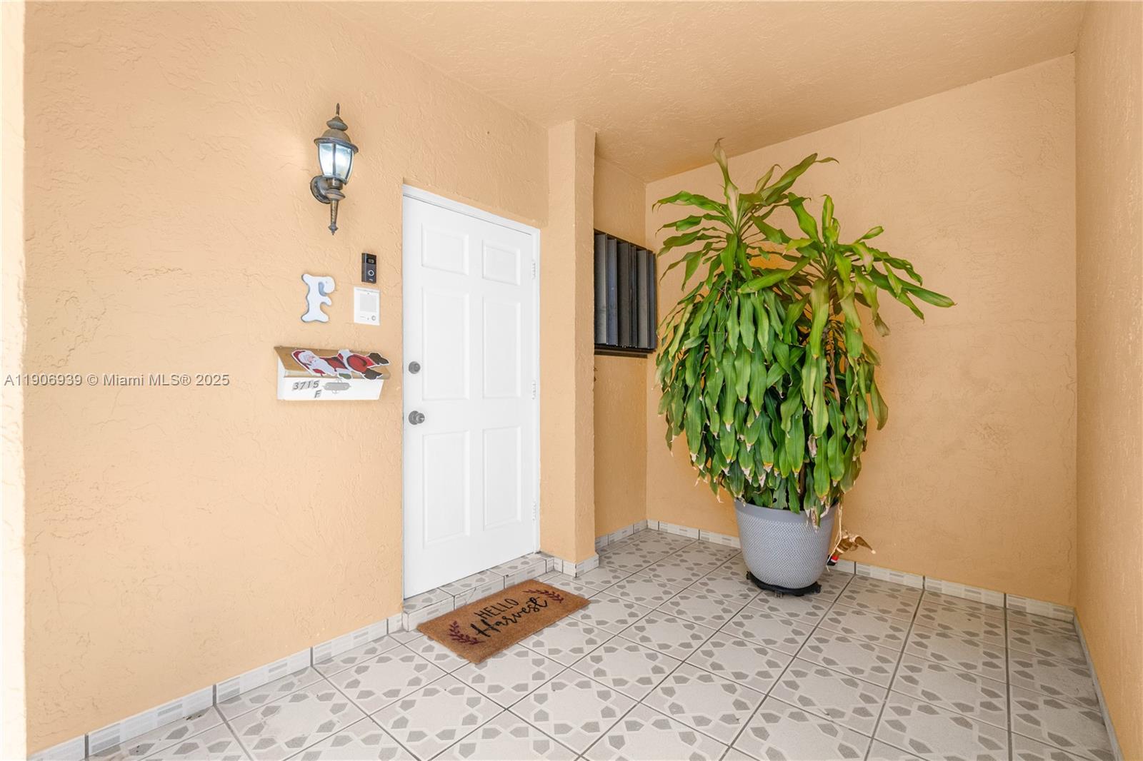 A covered entryway features a white door, a large potted plant, and patterned floor tiles — 13715 SW 84th St # F, Miami FL 33183, MIAMI, FL