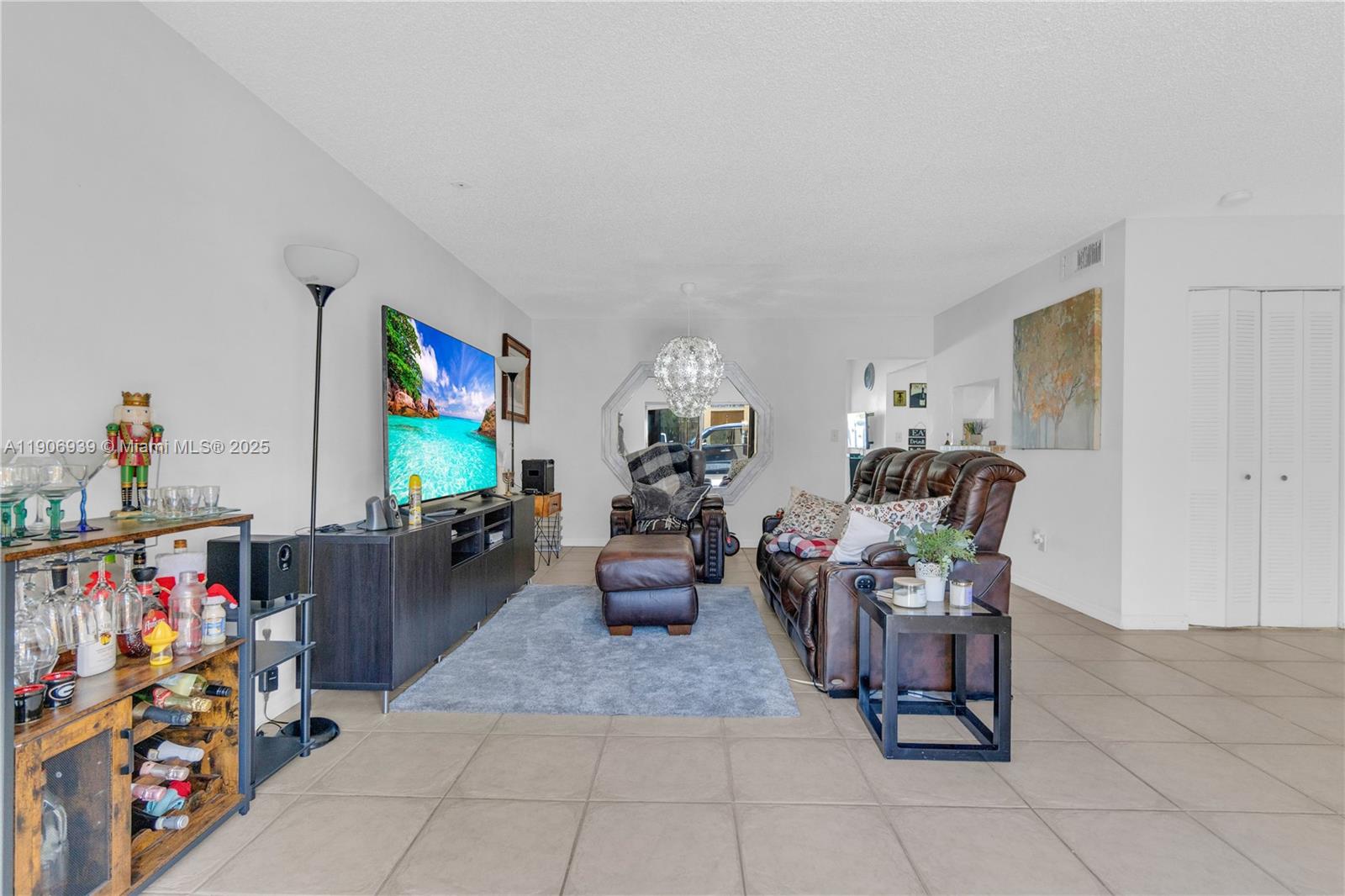 A living room features tile flooring, a brown leather sofa, and a television console — 13715 SW 84th St # F, Miami FL 33183, MIAMI, FL