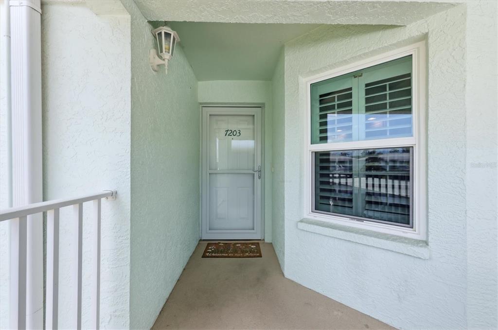 A light green exterior entryway features a white storm door and a single window — 5725 GREENWOOD AVENUE UNIT 7203, NORTH PORT, FL