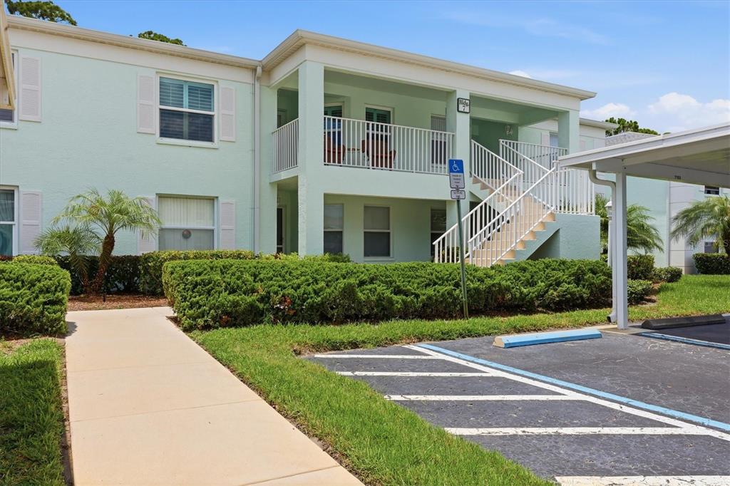 A two-story apartment building with a light green exterior, a staircase, and a parking lot — 5725 GREENWOOD AVENUE UNIT 7203, NORTH PORT, FL