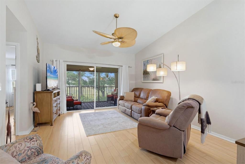 A living room features light wood flooring, a leather sofa, a recliner, and a sliding door — 5725 GREENWOOD AVENUE UNIT 7203, NORTH PORT, FL
