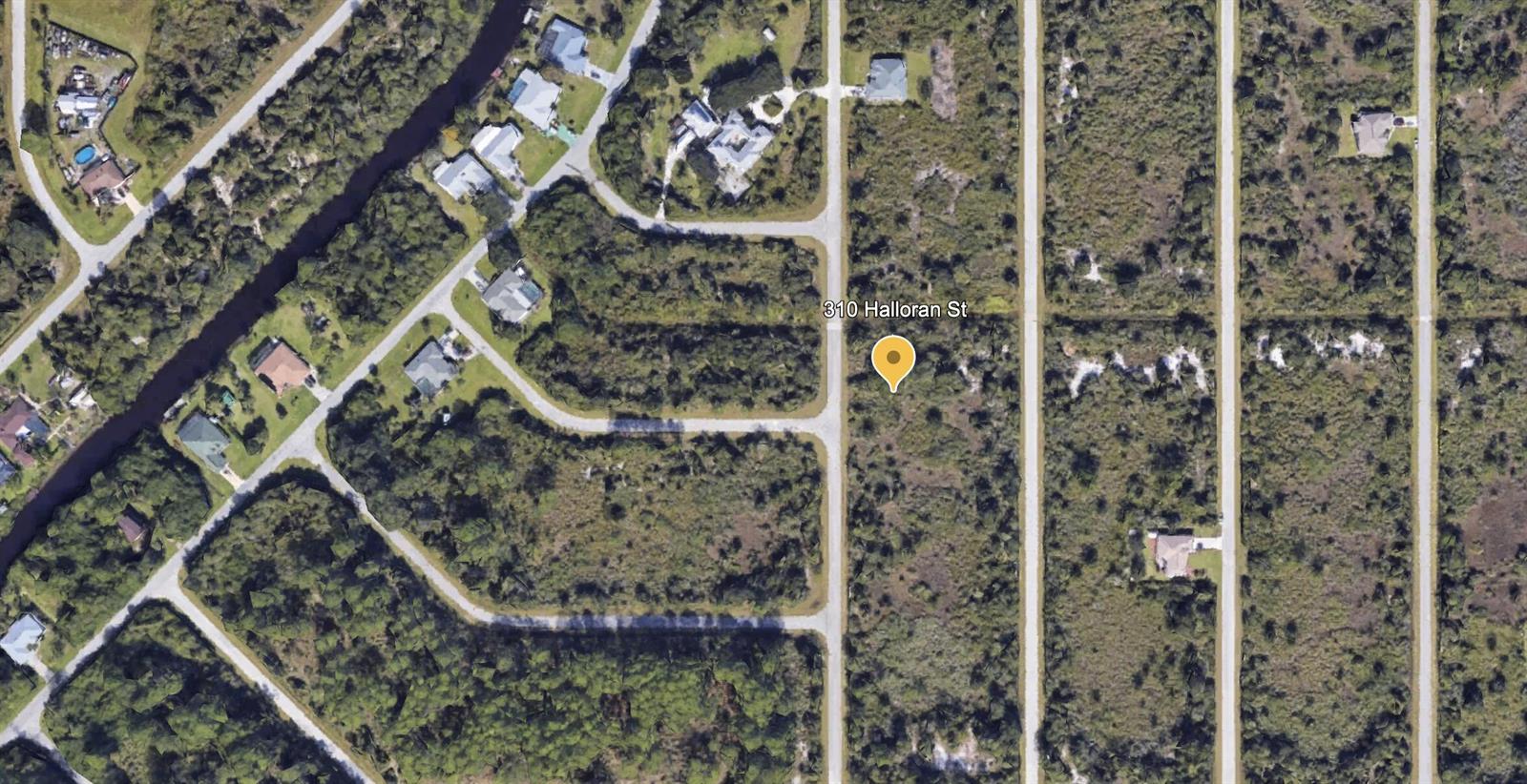 This aerial map view shows a vacant, wooded residential lot located at a street intersection — 310 Halloran Street, FL 33953, FL
