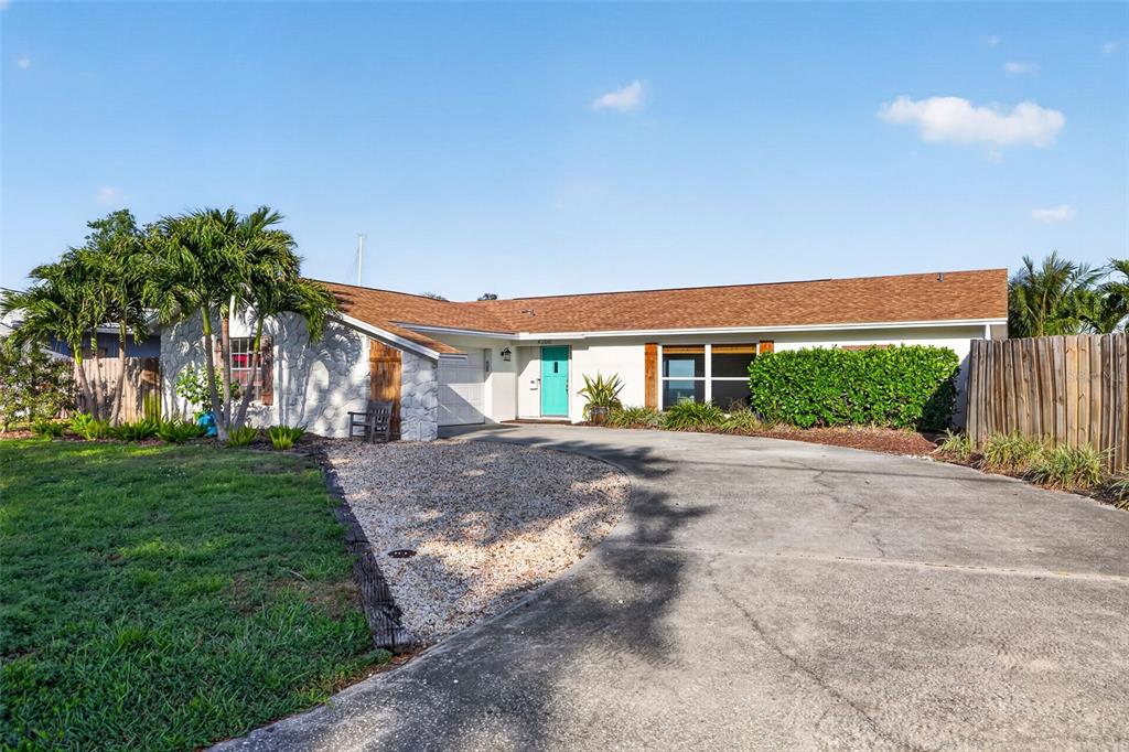 A single-story house features a white stone facade, a turquoise front door, and a driveway — 4200 BEACH DRIVE SE, ST PETERSBURG, FL