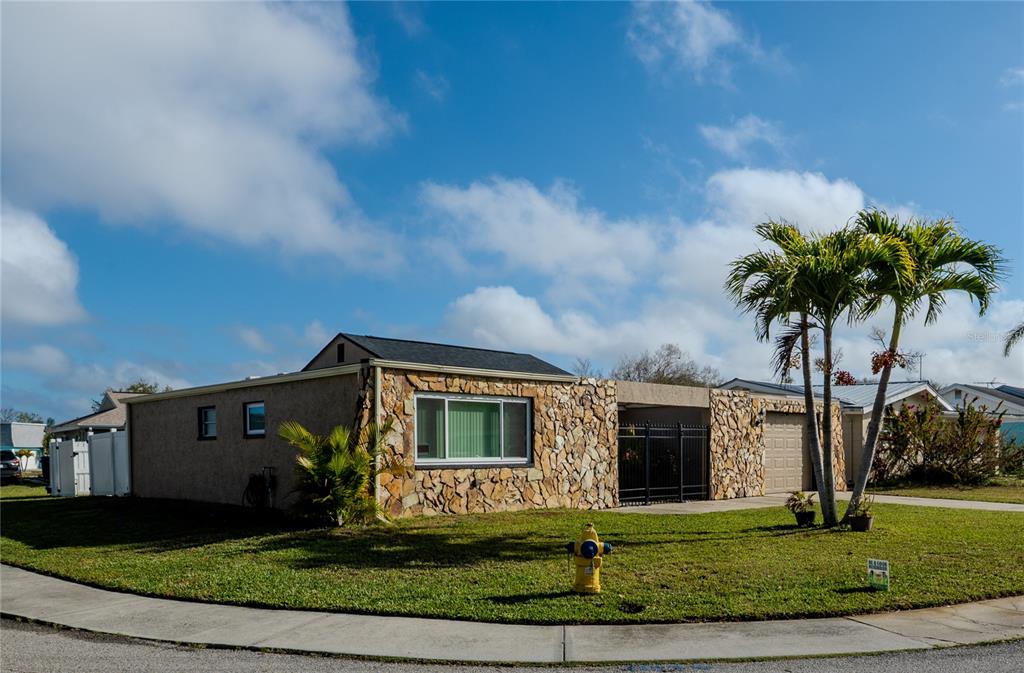 A single-story house with a stone facade, a flat roof, and palm trees in the yard — 3629 HAVEN DRIVE, NEW PORT RICHEY, FL