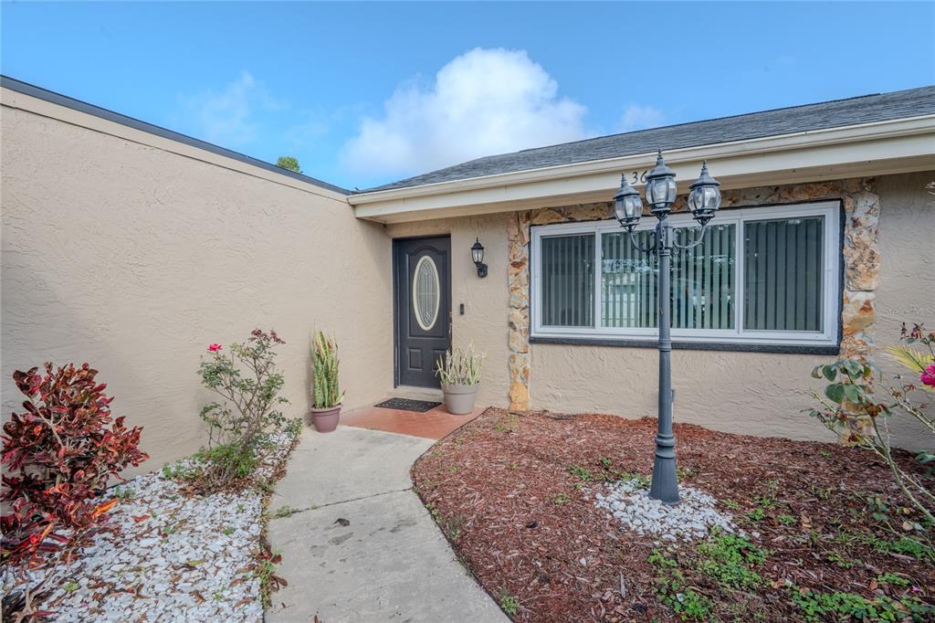 A concrete walkway leads to the front entrance of a house with stone accents — 3629 HAVEN DRIVE, NEW PORT RICHEY, FL