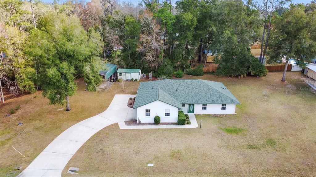 An aerial view of a white single-story house with a green roof and driveway — 12681 SE 54TH AVENUE, BELLEVIEW, FL