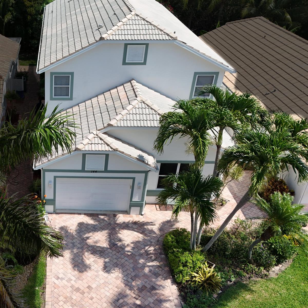 An aerial view shows a two-story white house with a tiled roof and brick driveway — 144 Pepper Lane, Jensen Beach FL 34957, JENSEN BEACH, FL