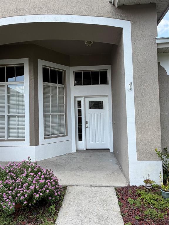 The exterior entrance features a white front door with a sidelight and transom window — 13813 BLUEWATER CIRCLE, ORLANDO, FL