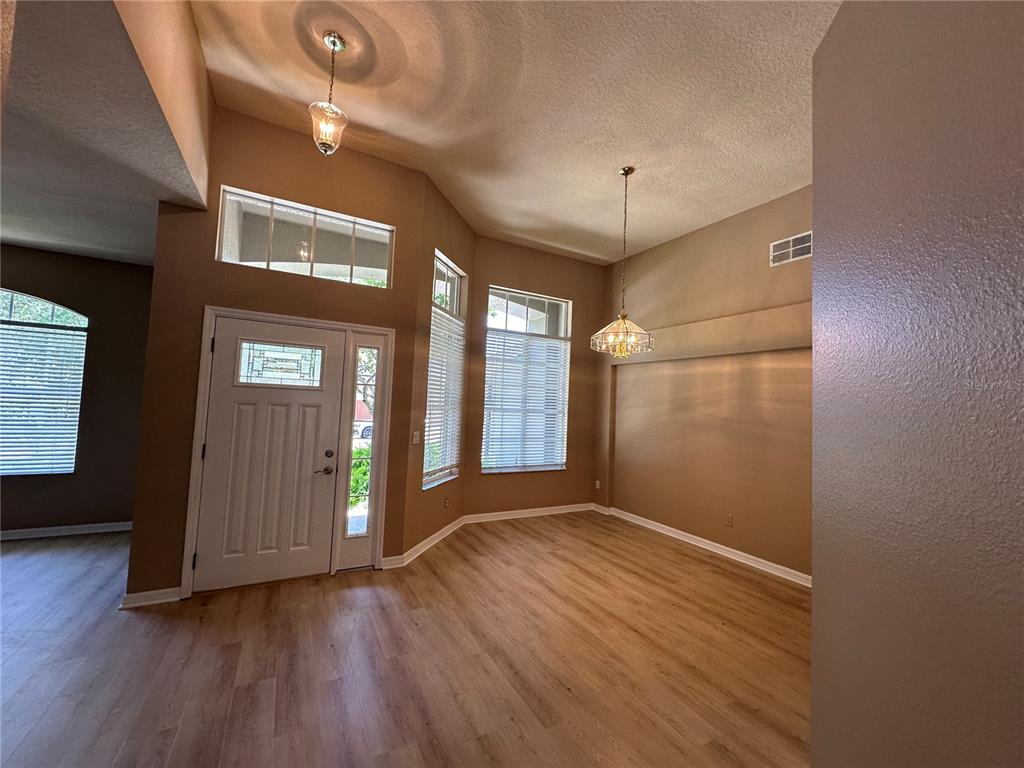 An entryway and dining area with high ceilings, light wood flooring, and large windows — 13813 BLUEWATER CIRCLE, ORLANDO, FL