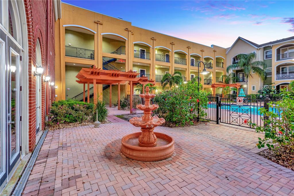 A brick courtyard features a tiered fountain, a wooden pergola, and a swimming pool area — 1810 E PALM AVE UNIT 6204, TAMPA, FL