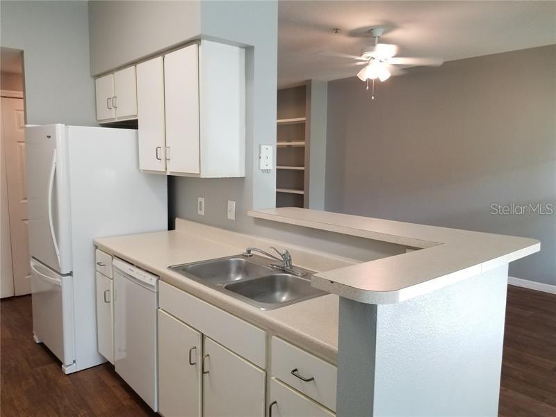 A kitchen with white cabinets, a white refrigerator, and a sink on a peninsula counter — 1810 E PALM AVE UNIT 6204, TAMPA, FL