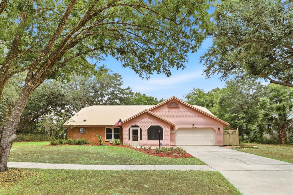A single-story house with a pink exterior, brick accents, and a metal roof — 3286 LAKE TWYLO ROAD, ORLANDO, FL