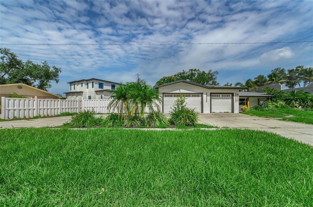 A single-story house with a two-car garage and a white fence sits behind a lawn — 850 RAFAEL BOULEVARD NE, ST PETERSBURG, FL