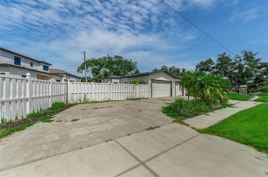 A concrete driveway leads to a detached garage behind a white vinyl privacy fence — 850 RAFAEL BOULEVARD NE, ST PETERSBURG, FL