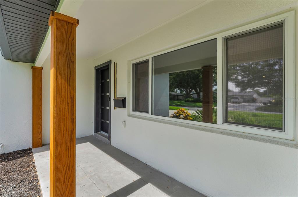 A covered porch features a dark front door, large windows, and wooden support posts — 850 RAFAEL BOULEVARD NE, ST PETERSBURG, FL