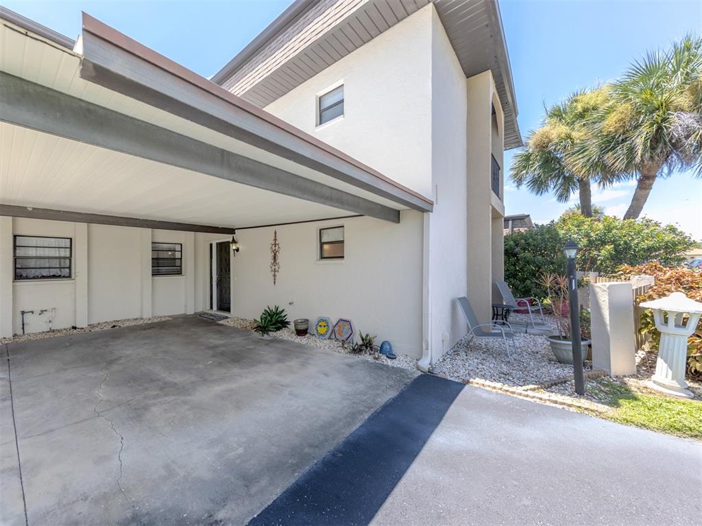 A concrete carport leads to the entrance of a two-story home with light-colored stucco walls — 1712 LAKESIDE DRIVE UNIT 1712-B, VENICE, FL
