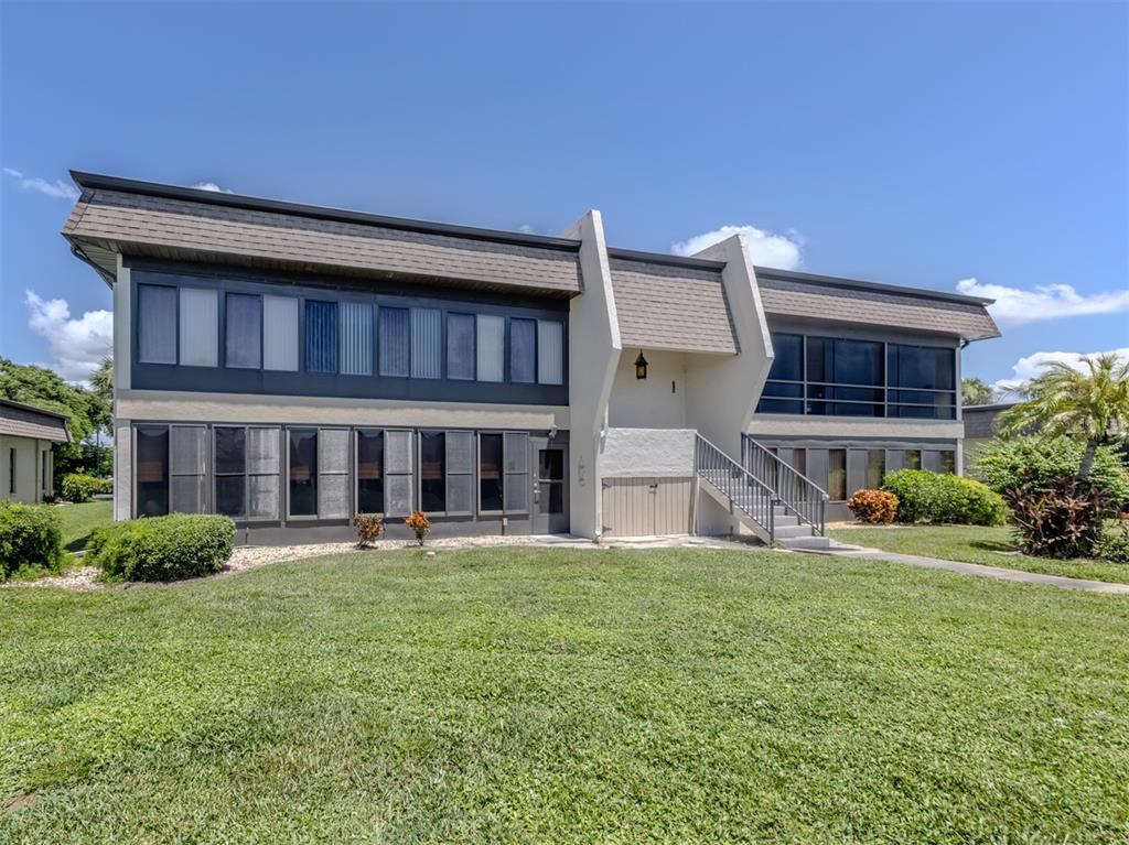 A two-story building with a brown mansard roof, dark window frames, and exterior stairs — 1712 LAKESIDE DRIVE UNIT 1712-B, VENICE, FL