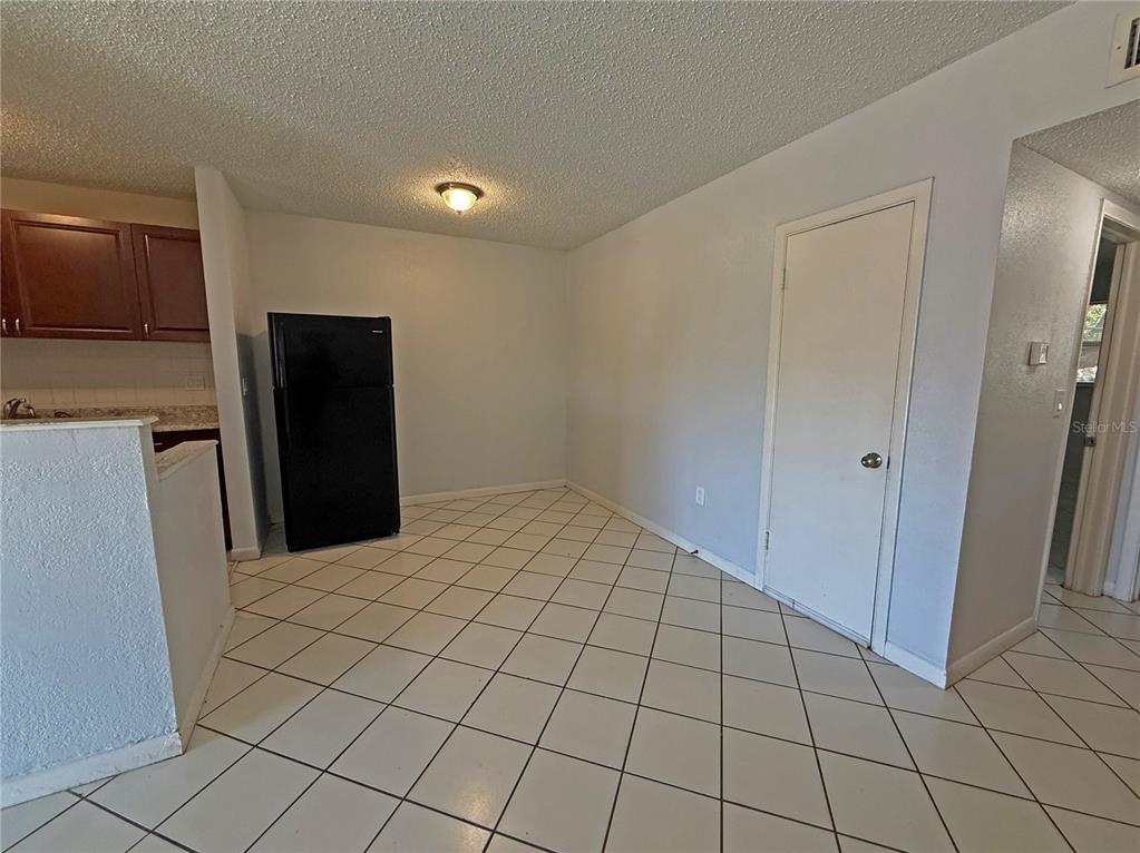A kitchen and dining area with white tile floors, a black refrigerator, and white walls — 2 N FERNWOOD AVENUE UNIT 14, CLEARWATER, FL