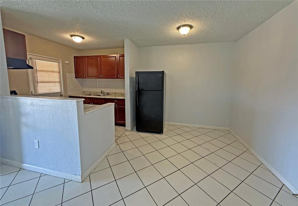 A kitchen with dark wood cabinets, a black refrigerator, and white tiled flooring — 2 N FERNWOOD AVENUE UNIT 14, CLEARWATER, FL