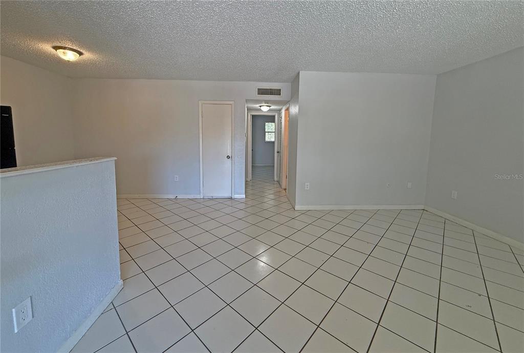 An empty room with white walls, a textured ceiling, and light-colored diagonal floor tiles — 2 N FERNWOOD AVENUE UNIT 14, CLEARWATER, FL