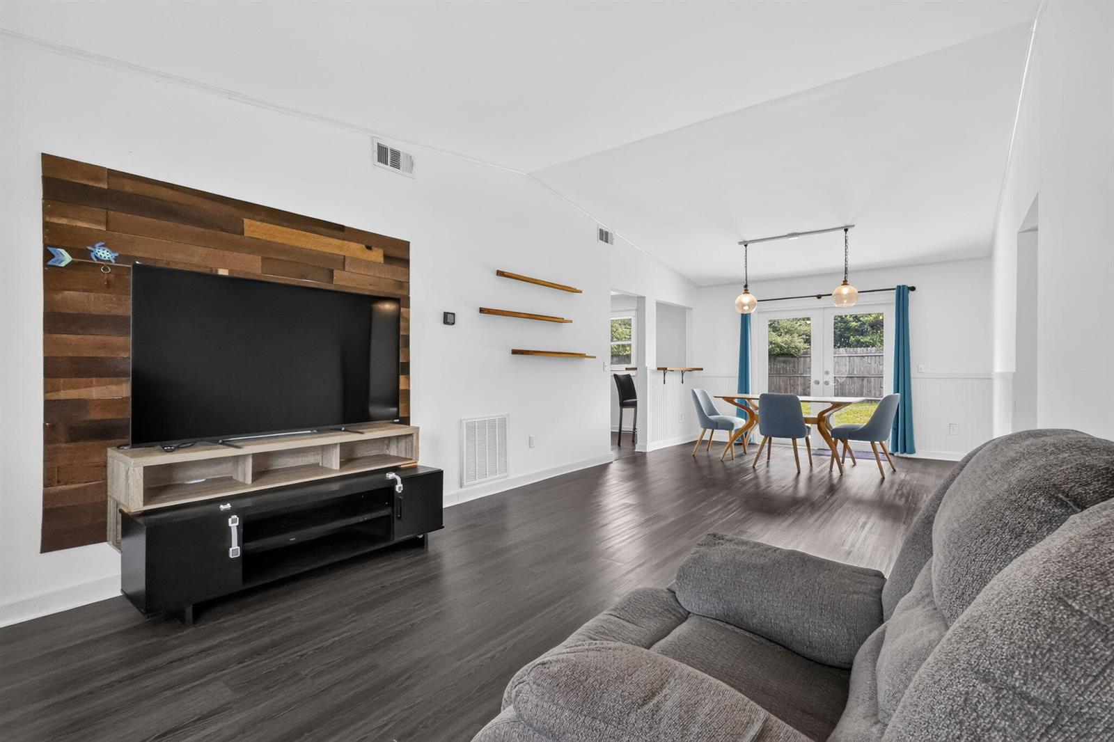 A living room with dark wood flooring, a wood-paneled accent wall, and a dining area — 5258 Canal Circle W, Lake Worth FL 33467, LAKE WORTH, FL